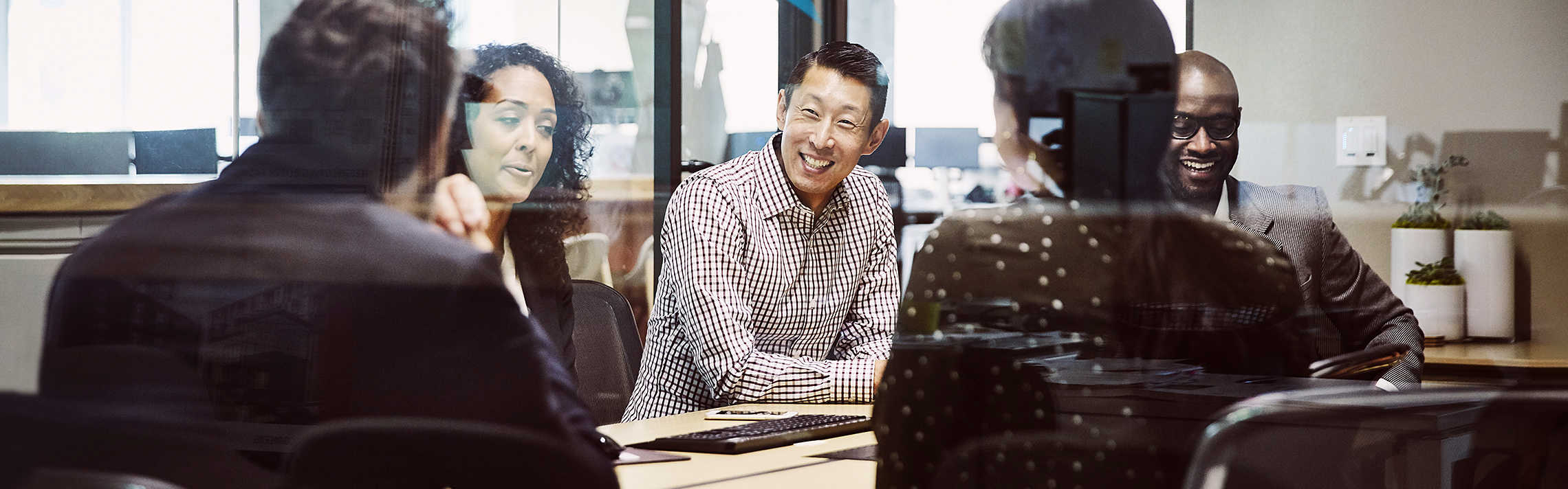 Smiling businessman leading client meeting in office conference room.